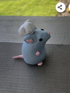 a toy mouse sitting on top of a cement floor next to a green grass field