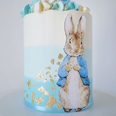 a blue and white cake decorated with an image of a rabbit holding a teddy bear