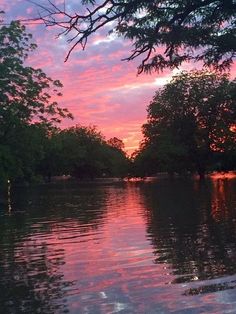 the sun is setting over some trees and water