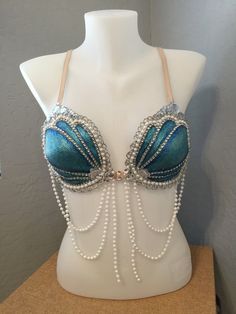 a white mannequin wearing a blue and silver bra with pearls on the side