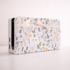 a cell phone case sitting on top of a white table with flowers and butterflies all over it