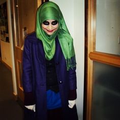 a woman wearing a green and purple hijab standing in front of a door