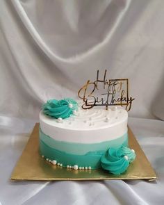 a white and blue birthday cake on a gold plate