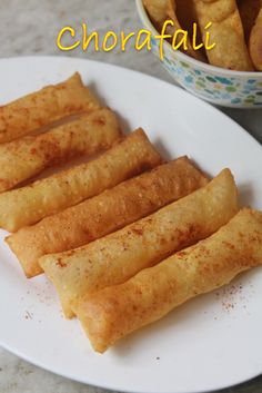 some food is on a white plate and next to a bowl of breadsticks