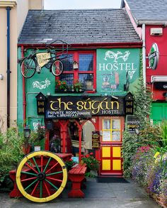 a colorful building with a wagon in front of it and flowers growing outside the window