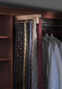 several ties are hanging on a rack in front of a wooden bookcase and white shirt