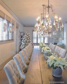 a long table with chairs and flowers on it in front of a large chandelier