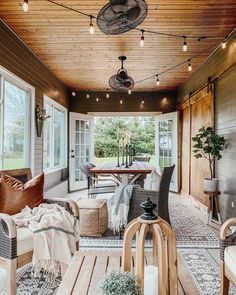 an outdoor living room with wood paneling and string lights hanging from the ceiling, along with wicker furniture