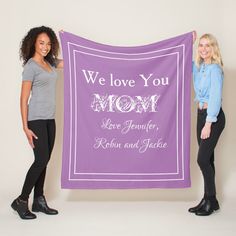 two women holding up a purple banner that says we love you mom