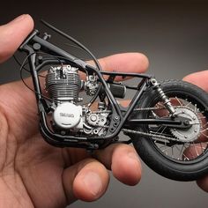 a miniature motorcycle is being held in the palm of someone's hand with it