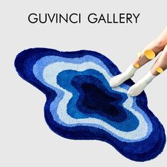 a pair of hands holding scissors over a blue and white rug with the words guvini gallery on it