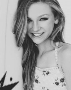 a beautiful young woman standing next to a surfboard