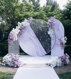 a purple and white wedding arch decorated with flowers