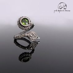 a ring with a green stone in the middle on top of a black surface,