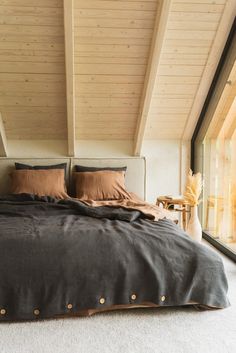 a large bed sitting under a wooden ceiling