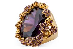 a ring with an oval shaped amethorate surrounded by purple and yellow stones