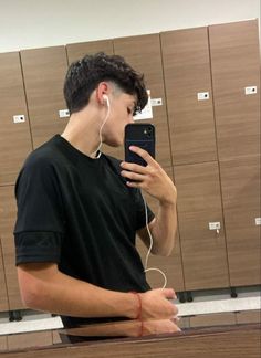 a young man is listening to music on his cell phone while standing in front of lockers