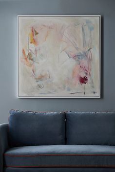 a blue couch sitting in front of a painting on the wall