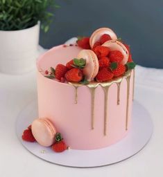 a pink cake with strawberries and icing drizzled on top