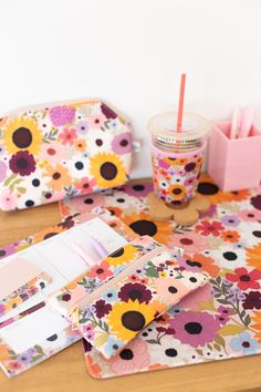 a wooden table topped with lots of colorful flowers next to a cup and pen holder