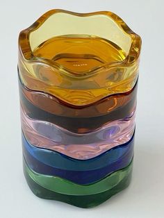 a stack of multicolored glass vases sitting next to each other on a white surface