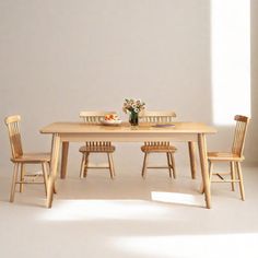 a wooden table with four chairs and a bowl of fruit on the dining room table