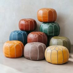 several different colored poufles sitting next to each other on the floor in front of a white wall