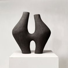 two black vases sitting on top of a white pedestal