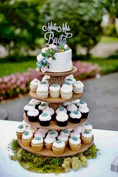 a three tiered cake with cupcakes on top