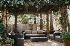 an outdoor living area with couches, tables and potted plants on the ground