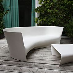 a white curved bench sitting on top of a wooden deck