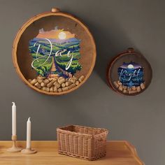 two wall hangings on the side of a table with wine glasses and candles in front of them