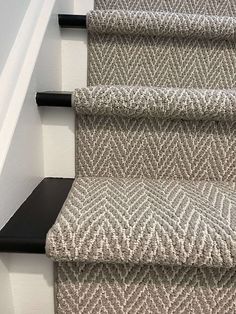 carpeted stairs with black handrails and white walls