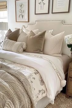 a bed with white sheets and pillows in a bedroom next to two pictures on the wall