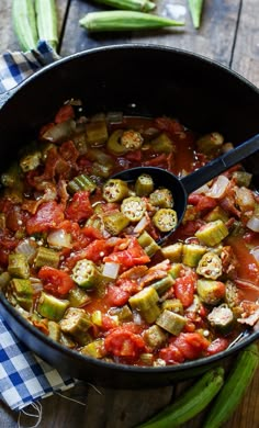 a pot filled with vegetables sitting on top of a wooden table next to green beans