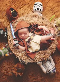 a baby is laying in a basket with toys on the floor next to it and wearing a star wars costume