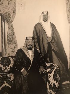 an old photo of two men sitting on a couch with one wearing a headdress