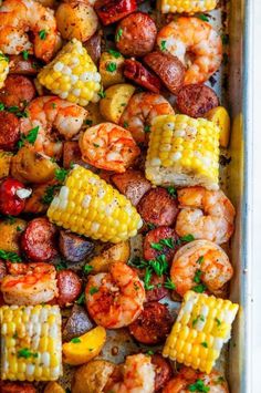 shrimp, corn on the cob and potatoes in a baking pan with parsley