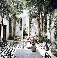 an outdoor dining area with black and white tile flooring, potted plants on the table