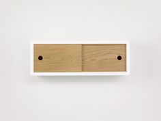 a white shelf with two wooden drawers mounted on it's side, against a white wall