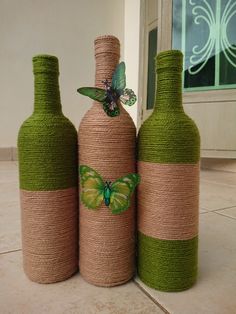 three green wine bottles wrapped in jute with a butterfly on the top and bottom