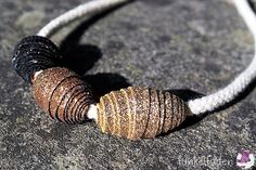 a close up of a bead on a stone surface with white string and black beads