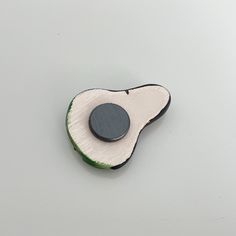 a piece of broccoli with a black button on it's side sitting on a white surface