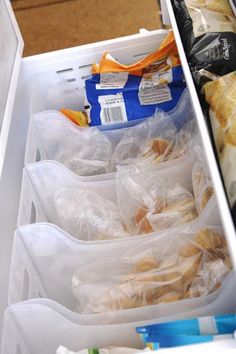 an open refrigerator filled with plastic containers and food in it's drawer, next to other items