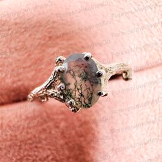 a woman's face wearing a ring with an oval stone