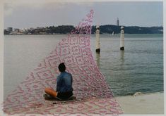 a man sitting on the edge of a body of water with pink lines covering him