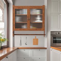 a kitchen with white cabinets and wooden counter tops next to a stove top oven in front of a window