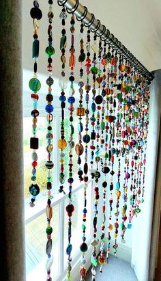 there is a long line of beads hanging from the wall in front of a window