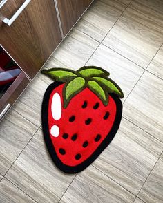 a red strawberry rug on the floor next to a cabinet and drawers in a kitchen