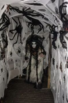 a person dressed in white and black walking through a tunnel with spider webs on it